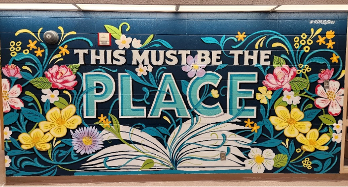 Mural at Vaughan Memorial Library depicting flowers growing around an open book with the text "This must be the place"